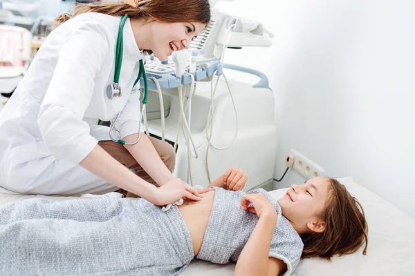 Social amigable médico femenino hablando con la niña mientras la examina —  Fotos de Stock