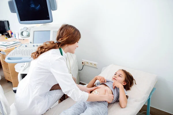 Dost canlısı bayan doktor, küçük kızların karnını inceliyor.