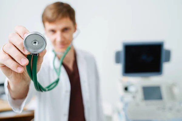 Cabeza de estetoscopio en la mano de un médico. De cerca. Borroso, enfoque en el objeto — Foto de Stock