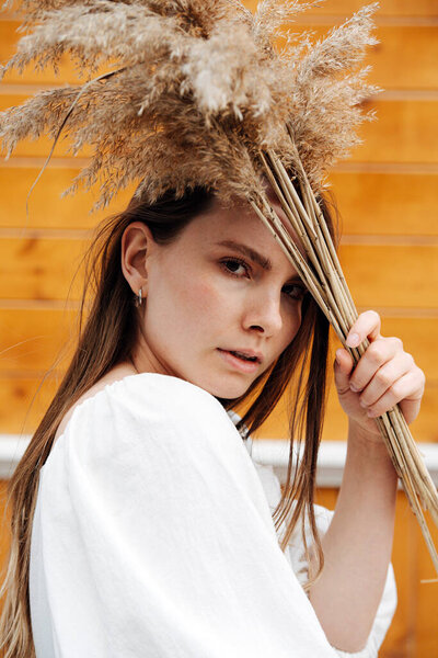 Портрет чувственной молодой женщины с букетом хлопьев у головы. Смотрю в камеру. Тело повернулось боком.