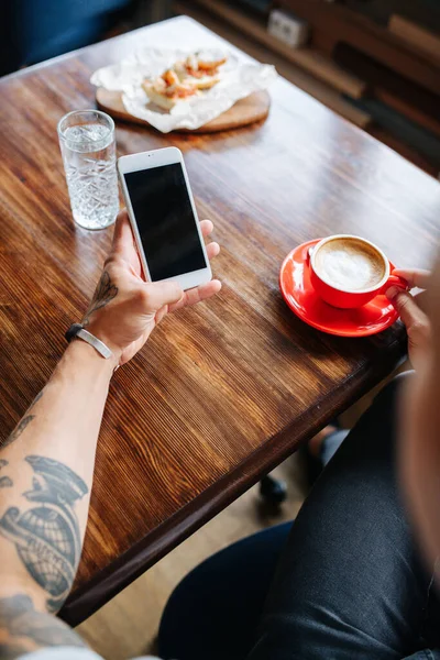 Bilde Tatovert Mann Som Drikker Kaffe Kafe Han Holder Telefonen – stockfoto