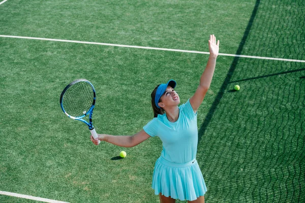 新しいテニスコートで空の青のスポーツ衣装の訓練で10代の女の子は 奉仕を練習し 空気中のボールを投げます 高角度 — ストック写真