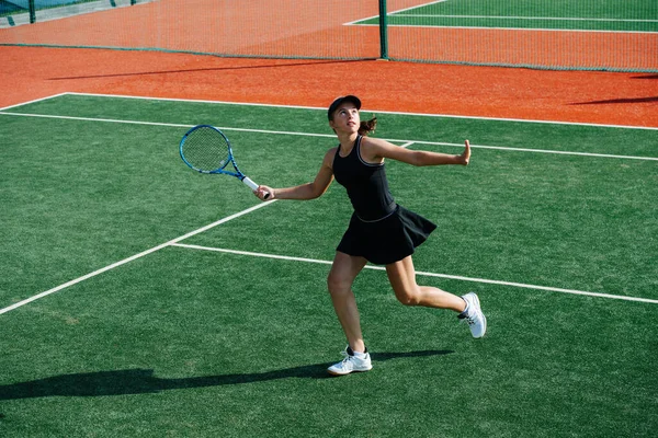 若いです女の子でA黒スポーツ衣装遊びテニス上のブランド新しい裁判所 リターンのオーバーヘッドボール — ストック写真