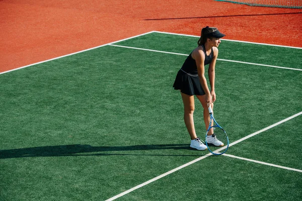 若いです女の子でA黒スポーツ服遊びテニス上の真新しい裁判所 上に傾いているラケット間セット — ストック写真