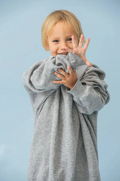 Cute little toddler boy in a huge oversized grey longsleeve over blue — Stock Photo, Image