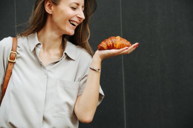 Gülümseyen olgun kadın avucunun içinde taze pişmiş kruvasan tutuyor. Ona bakıyorum..