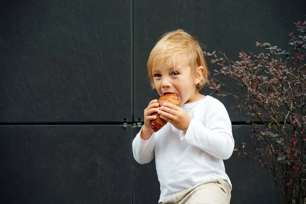 Menino Com Cabelo Loiro Comendo Croissant Crocante Fresco Com Apetite — Fotografia de Stock