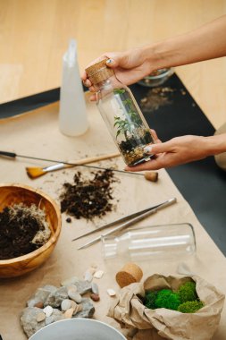 Kapalı alanda bahçede bitki yetiştirme temalı şeyleri şişenin içinde tutan eller..