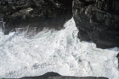 İrlanda'nın güneybatısında sahilde kayalar ve fırtınalı su, Mizen Head