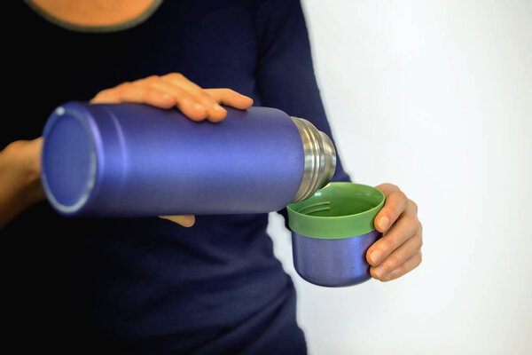 Голубой термос в женских руках. Close view
.