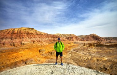 Turist çöl park altun Emel Kazakistan'ın arka planda gerçeküstü kırmızı ve sarı dağ ile yeşil ceketli