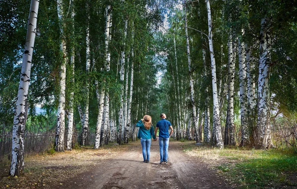 Happy couple in checked shirts on the road in birch wood in Kyrgyzstan. Romantic date in the forest.