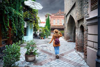 Turist kadın kahverengi şapkalı yaşlı merkezi Tiflis, Gürcistan eski sokaklarında yürüyüş