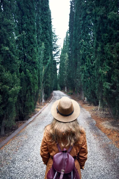 トビリシ グルジアの植物園のサイプレス路地を見てのバックパックと黒い帽子の女 — ストック写真