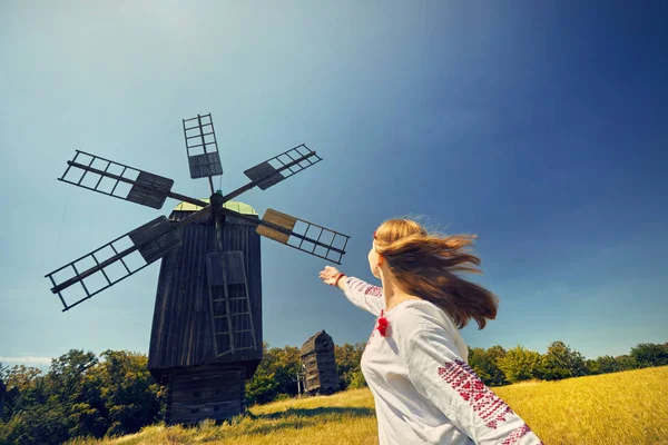 Pirogovo 国立建築博物館で白のエスニック シャツ木製風車のそばで踊って美しいウクライナの女の子 キエフ ウクライナ — ストック写真