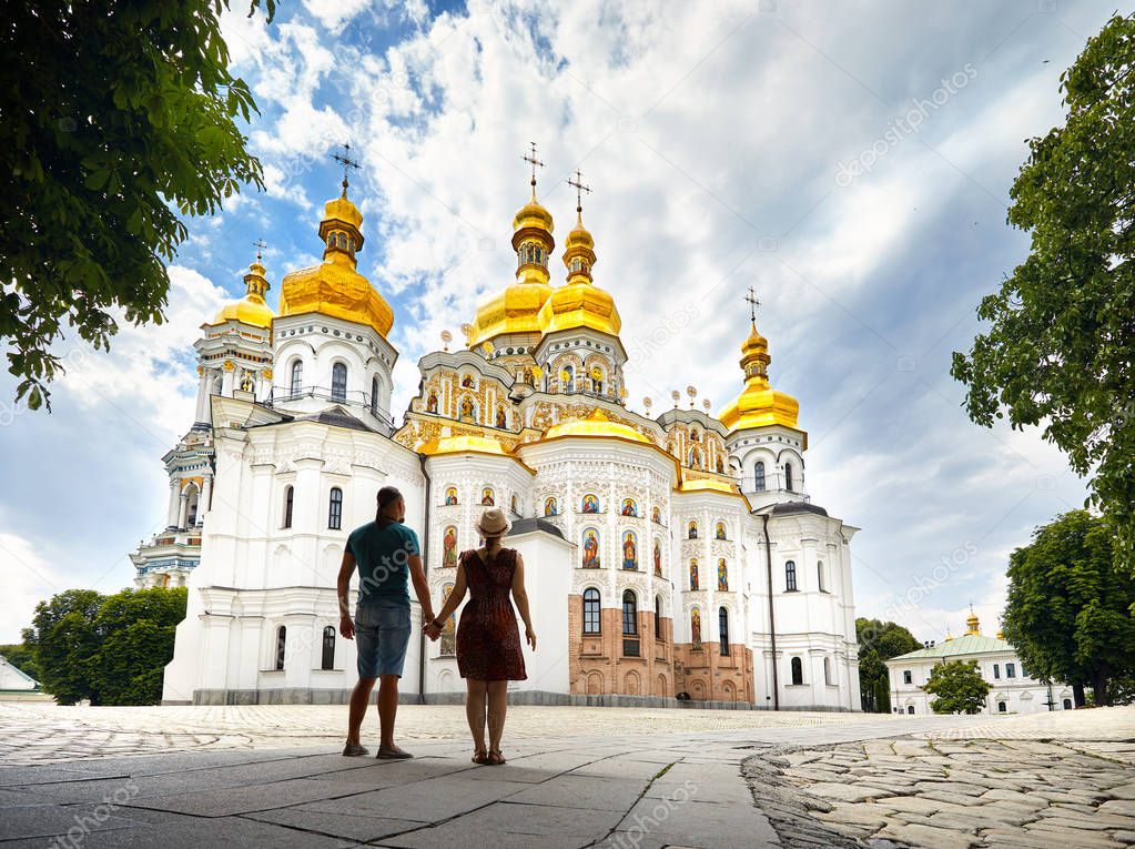 Young tourist couple in silhouette looking at Church with golden domes at Kiev Pechersk Lavra Christian complex. Old historical architecture in Kiev, Ukraine