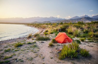 Kırgızistan'daki kıyı Issyk Kul dağ Gölü üzerinde turuncu çadır
