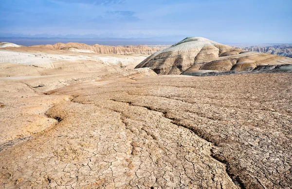 Landscape of cracked ground and mountains in the desert. National desert park Altyn Emel in Kazakhstan