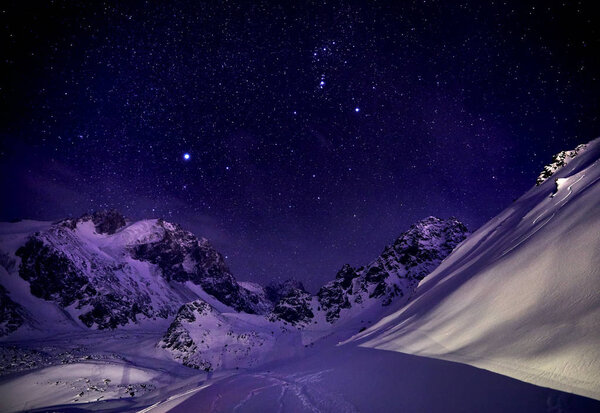 Beautiful winter landscape of the snowy mountains against starry night sky