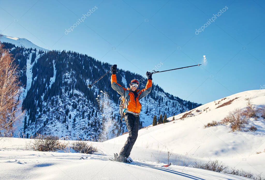 Happy Man raising his hand and skiing on fresh powder snow at forest in the Tien Shan Mountains, Kazakhstan