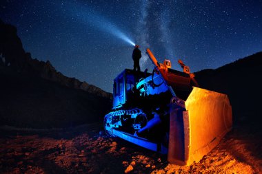 Gece gökyüzü ile buldozer üzerinde Adam