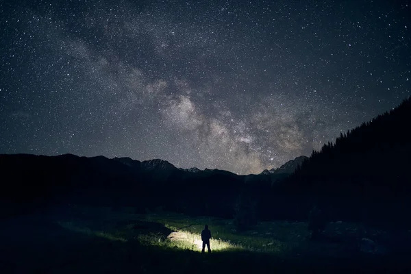 인간의 실루엣은 밤하늘의 산에서 전조등으로 밝히고 — 스톡 사진