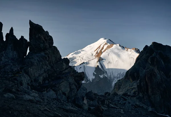 澄んだ青い空に黒い岩のシルエットで雪の山のピークフレーミングの美しい風景 — ストック写真