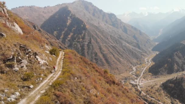 Чоловік їде на велосипеді по гірській дорозі, знятій безпілотником — стокове відео
