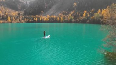 Adam dağdaki gölde Sup 'ın üzerinde kürek çekiyor.