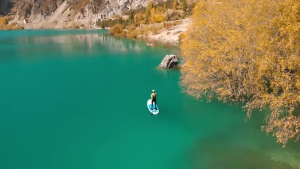 男は山の湖でスップボード上で漕いでいる — ストック動画