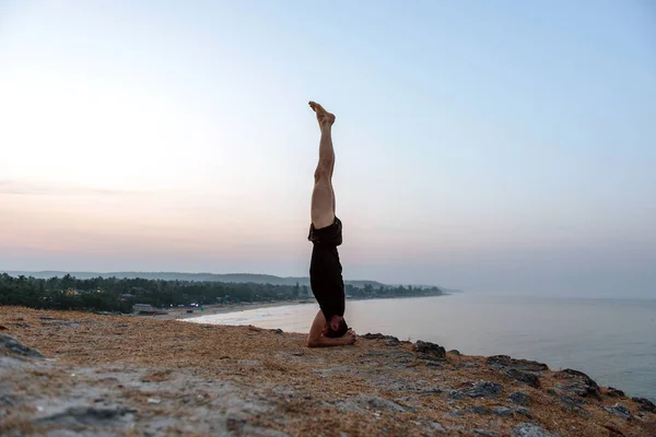 Zdravý člověk cvičí jógu pod na pláži při západu slunce. — Stock fotografie