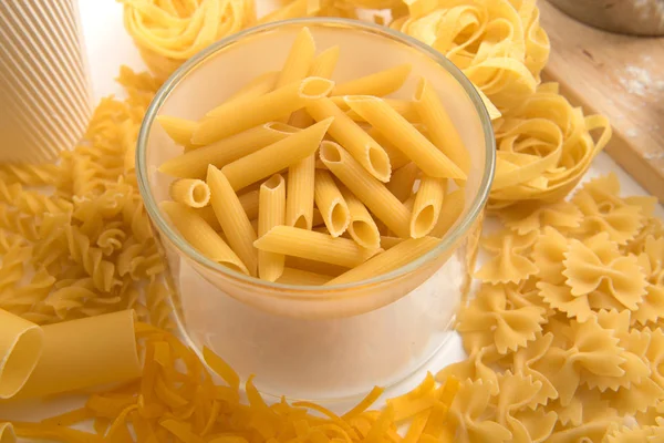 Tema da pasta. Diferentes tipos de macarrão em um fundo de madeira. Farfalle, fettuccine, macarrão, fusilli e penne rigate — Fotografia de Stock