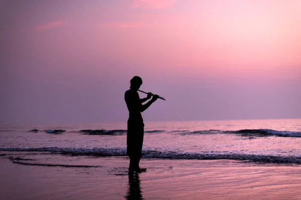 Un homme s'entraîne à jouer de la flûte sur le bouleau au coucher du soleil. GOA, Inde. 16.01.2018 — Photo