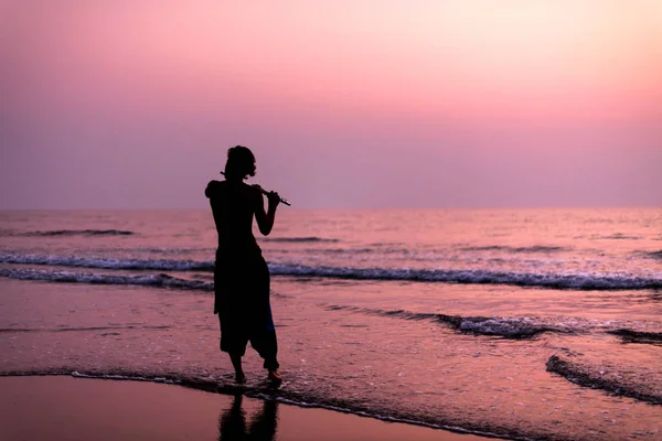 Un homme s'entraîne à jouer de la flûte sur le bouleau au coucher du soleil. GOA, Inde. 16.01.2018 — Photo