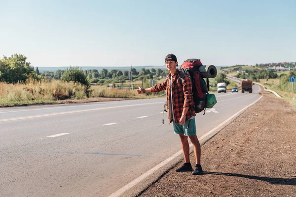 Travel man hitchhiking. Backpacker on road