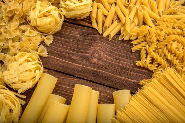 Yapıştır tema. Ahşap arka plan üzerinde makarna çeşitleri. Farfalle, fettuccine, erişte, düdük ve penne rigate