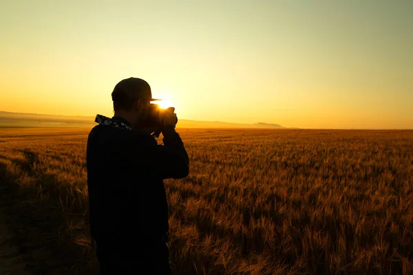 Man take a photo in sunrise in field — Stock Photo, Image