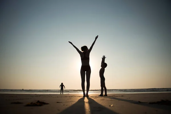 Femme pratiquant le yoga avec enfant sur la plage au coucher du soleil — Photo