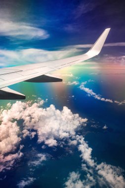 Gökkuşağı etkisi ile bulutlu gökyüzünde uçağın Kanadı