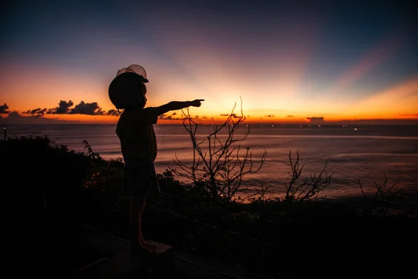 Un garçon dans un casque regarde le coucher du soleil en mer sur le point de vue — Photo