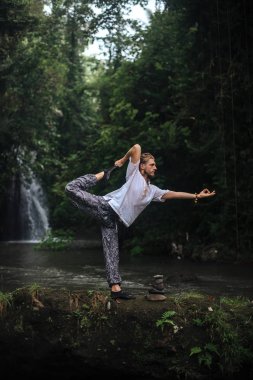 Yoga uygulaması ve doğada meditasyon. Nehir yakınlarında pratik yapan adam