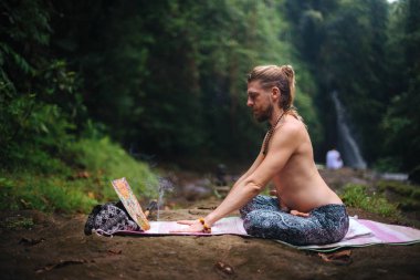 Yoga uygulaması ve doğada meditasyon. Nehir yakınlarında pratik yapan adam