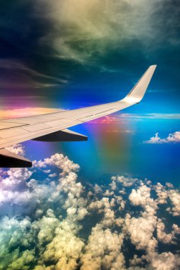 Gökkuşağı etkisi ile bulutlu gökyüzünde uçağın Kanadı
