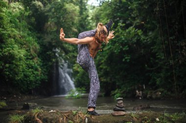 Yoga uygulaması ve doğada meditasyon. Nehir yakınlarında pratik yapan adam