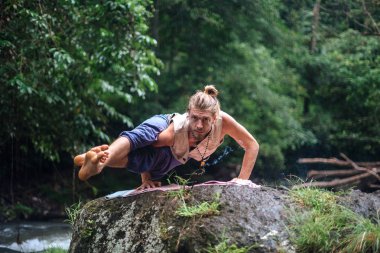 Yoga uygulaması ve doğada meditasyon. Nehir yakınlarında pratik yapan adam