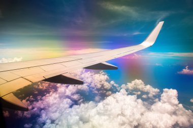 Gökkuşağı etkisi ile bulutlu gökyüzünde uçağın Kanadı