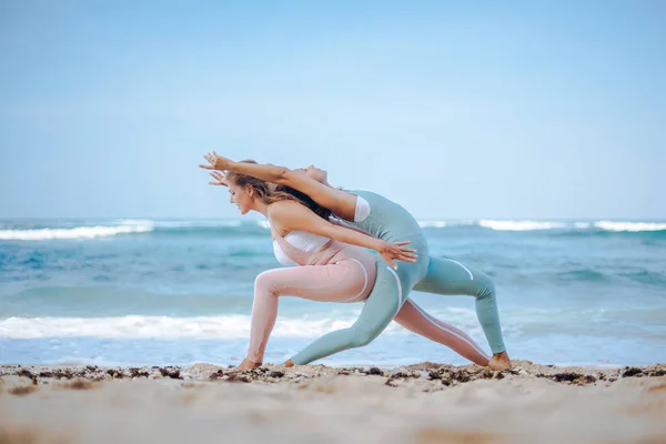 Coppia di ragazze pratica yoga sullo sfondo dell'oceano — Foto Stock