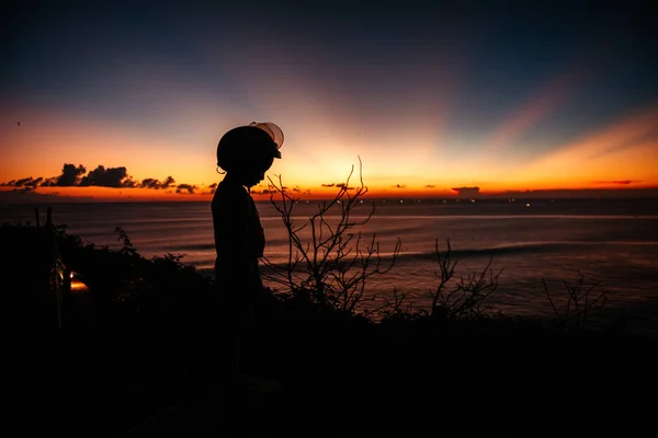 Un garçon dans un casque regarde le coucher du soleil en mer sur le point de vue — Photo