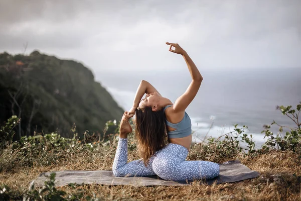Chica practica yoga cerca del océano . — Foto de Stock