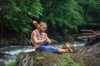 Yoga uygulaması ve doğada meditasyon. Nehir yakınlarında pratik yapan adam
